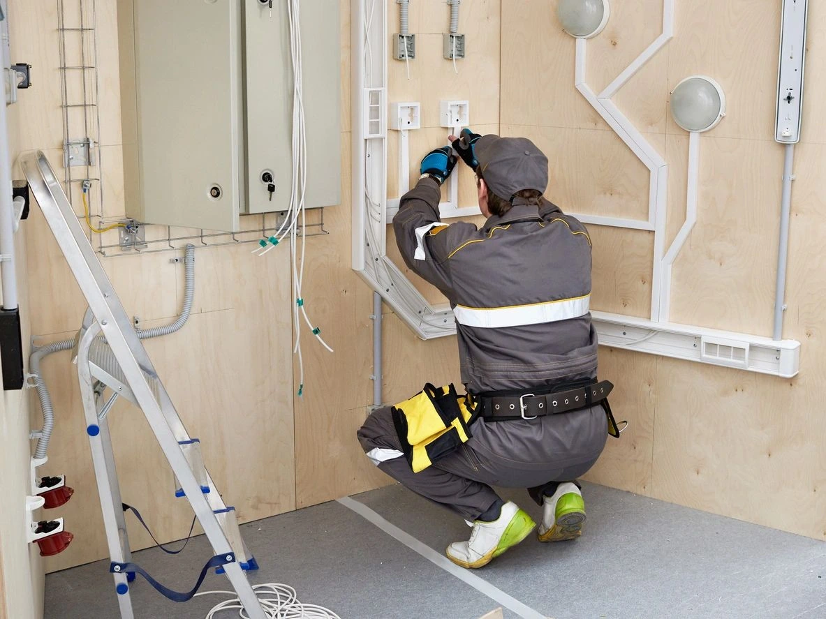 A man in grey work suit working on electrical wiring.